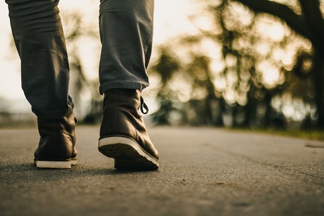 de benen en schoenen van iemand die wandelt op straat.