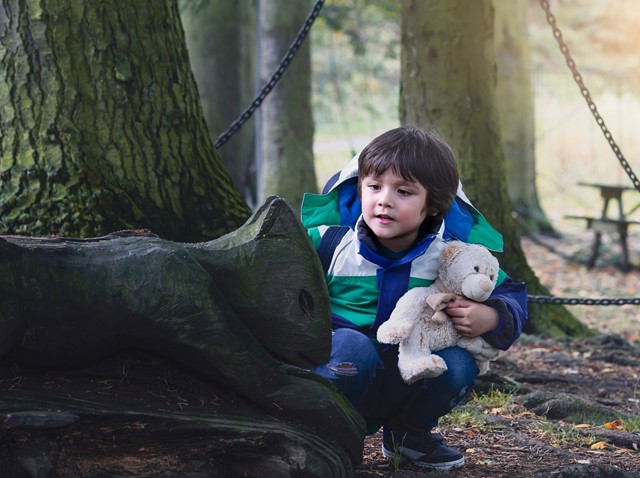 Kind in het bos met een knuffel
