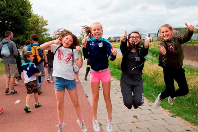 Avond4daagse: een wandelfeestje voor iedereen; vier meiden springen vrolijk in de lucht