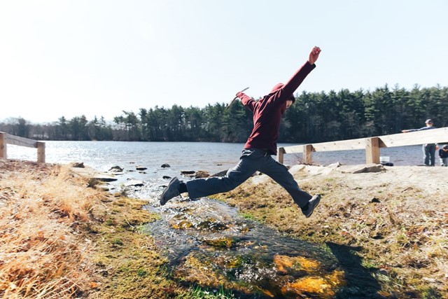 Barefoot wandelen, waarom wel en waarom niet?; jongen springt over sloot