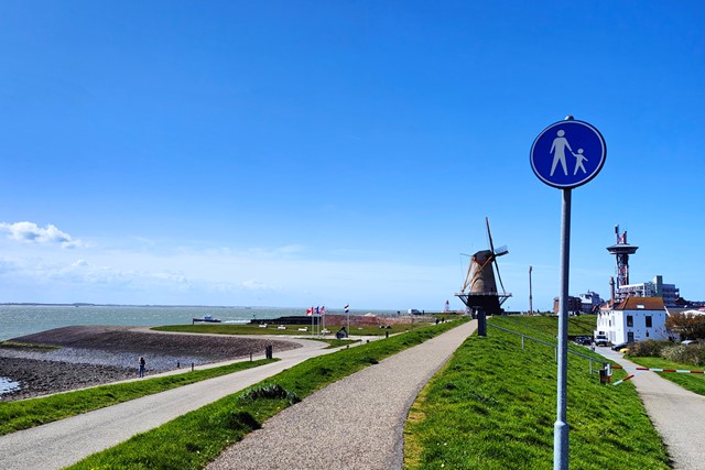 afbeelding van Uncle Beach Vlissingen, met een molen, voetpad, de zee.