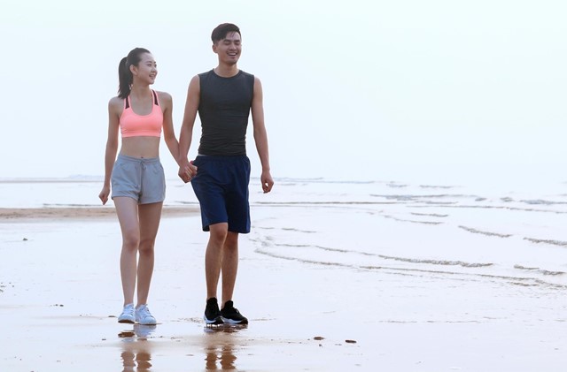 Man en vrouw wandelen hand-in-hand op strand